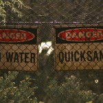 A photo of danger signs that warn of acid water and quicksand.