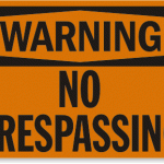 An orange sign reading: warning no trespassing