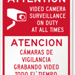 Bi-lingual sign that reads "Attention video camera surveillance on duty at all times" in English and Spanish.