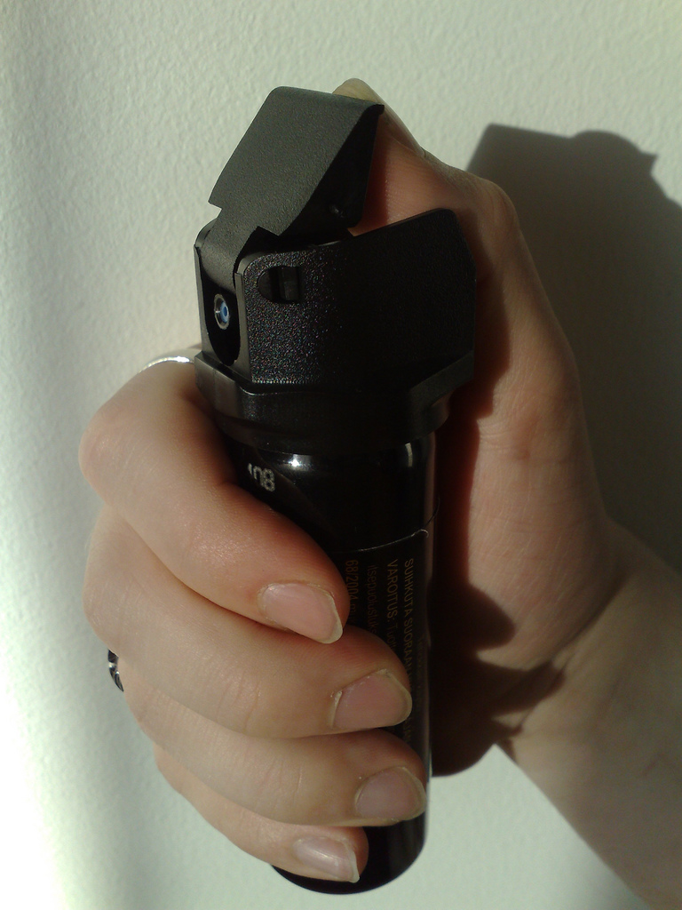 pepper-spray hand holding a black canister of pepper spray