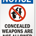 Sign reading Notice: Concealed weapons are not allowed. Image of a gun and knife crossed out.