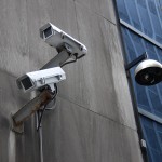 Surveillance cameras mounted on the side of building.